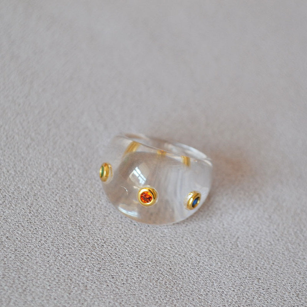 A transparent resin ring set with colored zircon