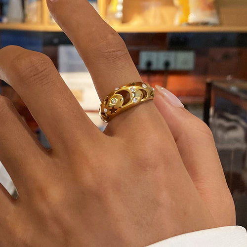 A stainless steel ring with diamond-encrusted and hollowed-out stars and moons