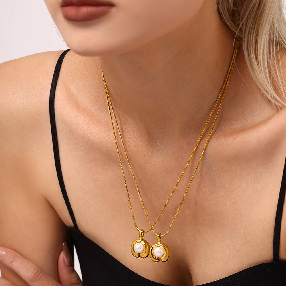 A C-shaped freshwater pearl pendant necklace made of stainless steel plated with 18K gold