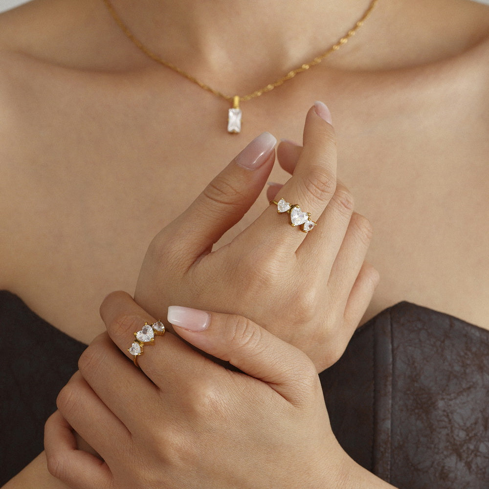 A stainless steel ring set with three heart-shaped zircon stones