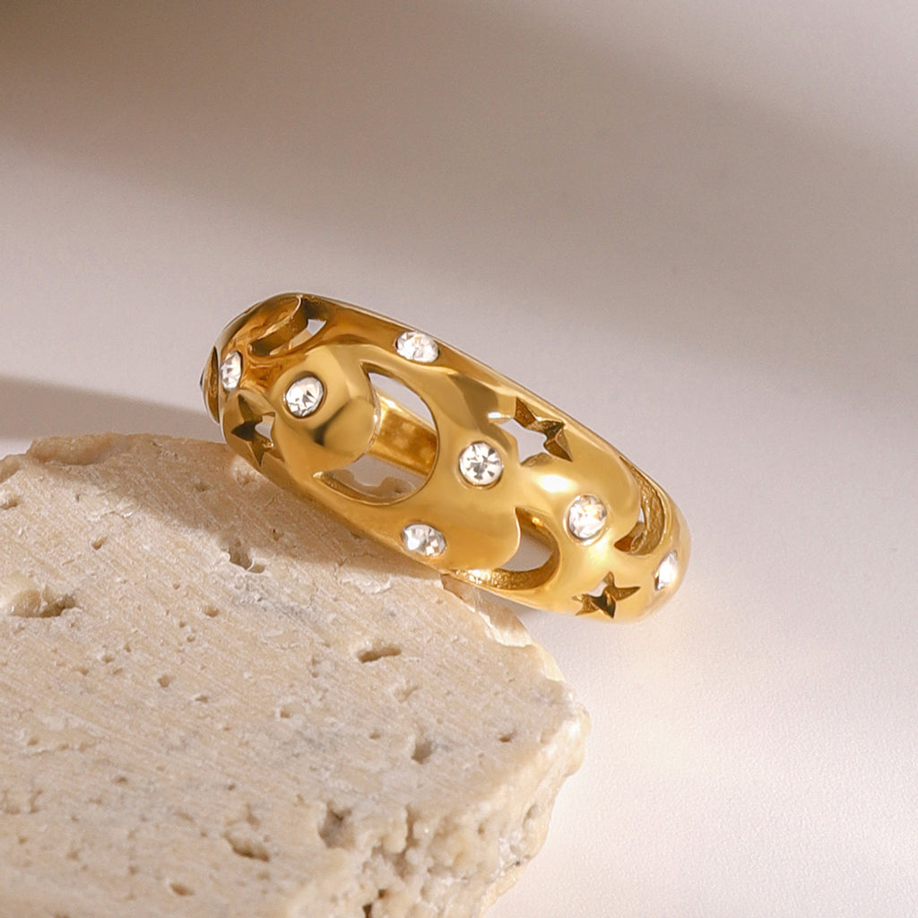 A stainless steel ring with diamond-encrusted and hollowed-out stars and moons