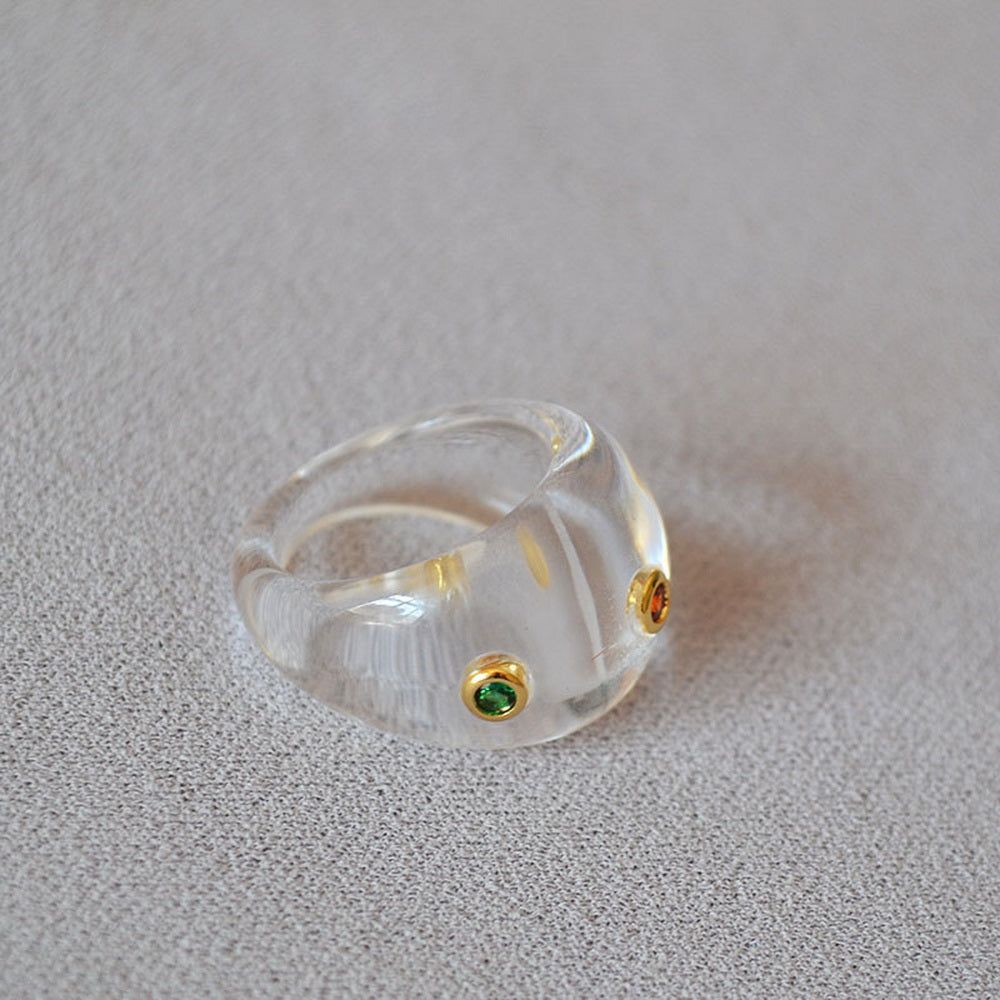 A transparent resin ring set with colored zircon
