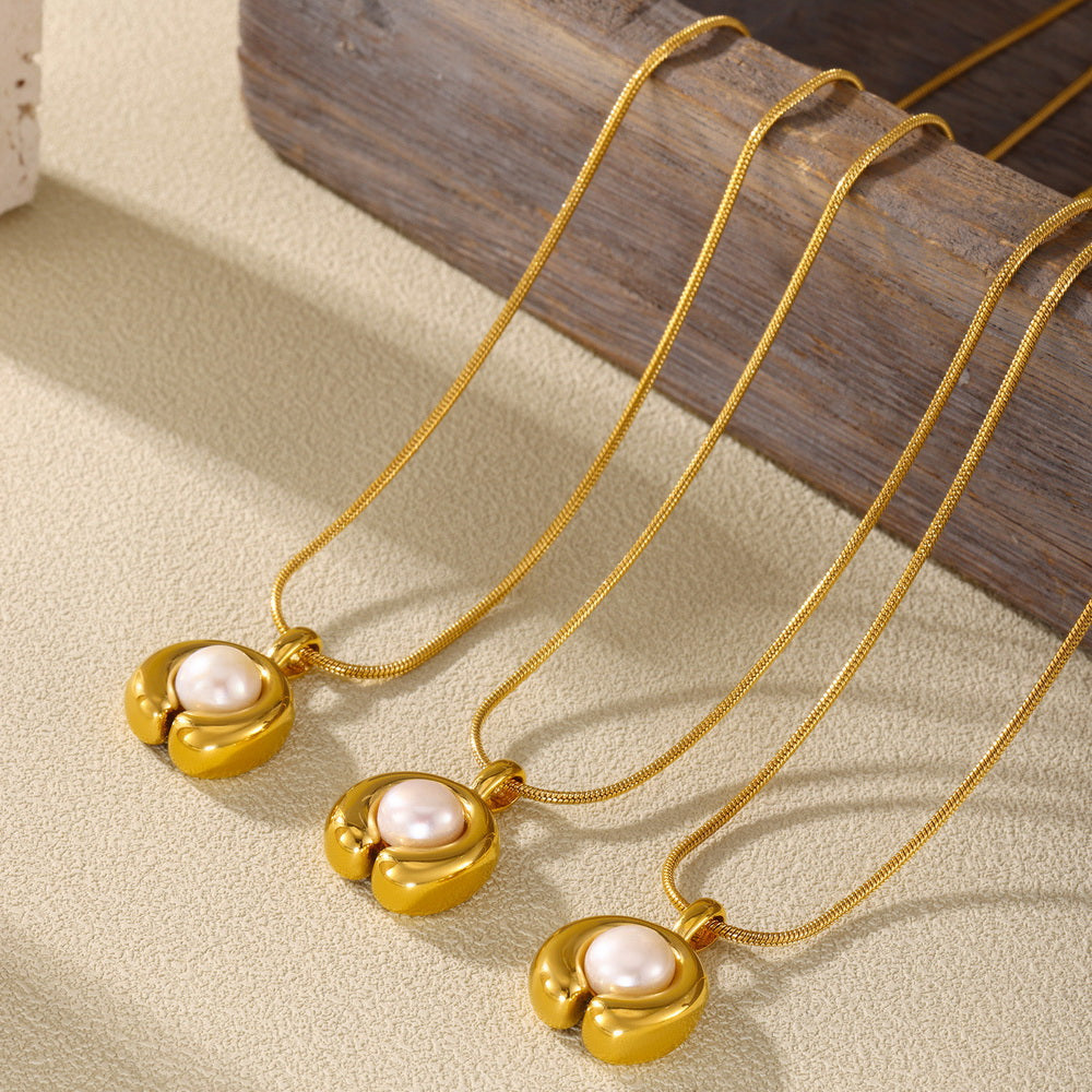 A C-shaped freshwater pearl pendant necklace made of stainless steel plated with 18K gold