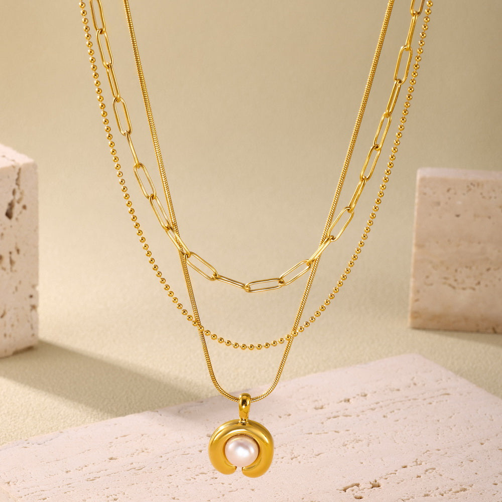 A C-shaped freshwater pearl pendant necklace made of stainless steel plated with 18K gold