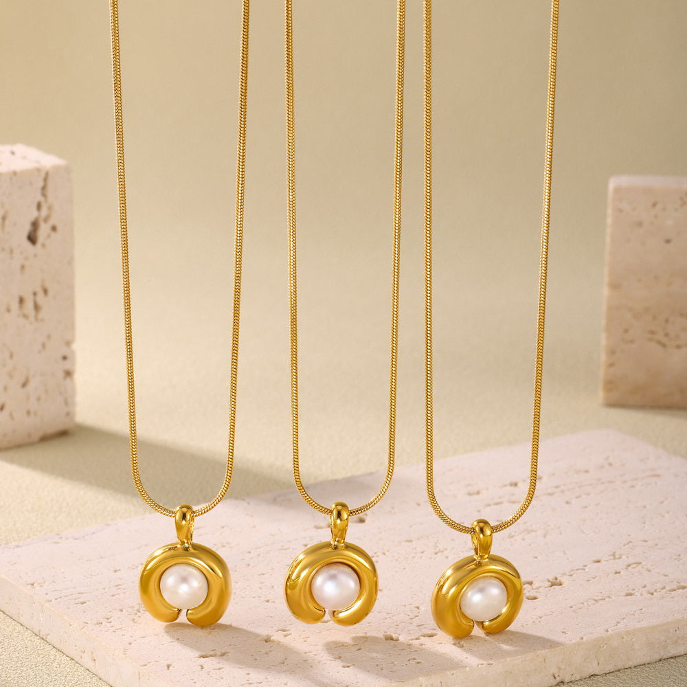 A C-shaped freshwater pearl pendant necklace made of stainless steel plated with 18K gold