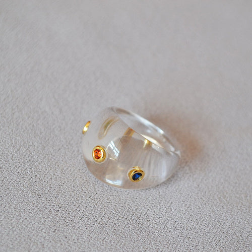 A transparent resin ring set with colored zircon